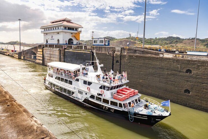 A riverboat docked at a lock, with a bridge and a building in the background. 2