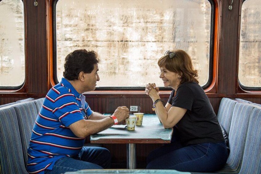 Dos personas sentadas en una mesa dentro de un vagón de tren. 5