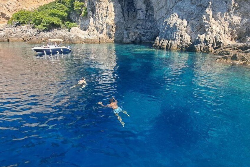 A clear blue sea with a boat and a diver. 1