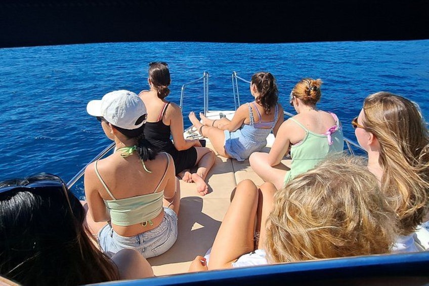 A group of people on a boat, facing the water. 4
