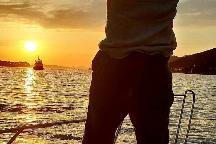 A person standing on a boat with a sunset in the background. 2