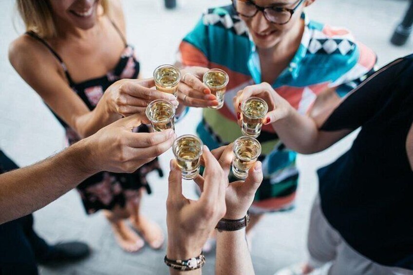 Eine Gruppe von Personen hält Schnapsgläser und scheint einen Toast auszubringen. 1