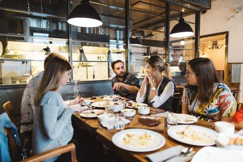 Un grupo de personas cenando en un restaurante con mesas de madera y lámparas colgantes. 1