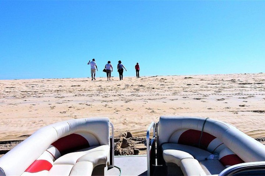 En strand med folk, der går mod vandet, en båd og en klar himmel. 3
