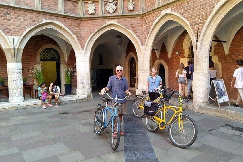 Une cour avec des arcades en briques, deux vélos et des gens qui se promènent. 2