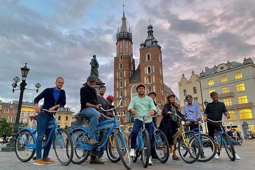 Un groupe de personnes à vélo devant un bâtiment historique doté d’une haute tour. 1