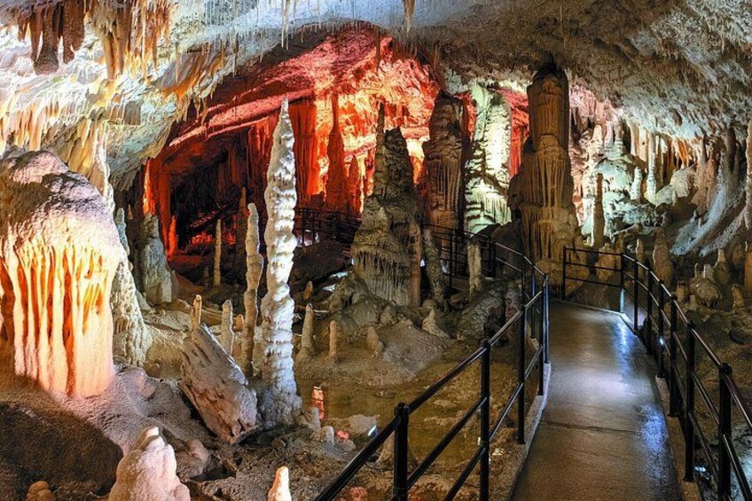 A cave with stalactites and stalagmites, a pathway, and a railing. 5