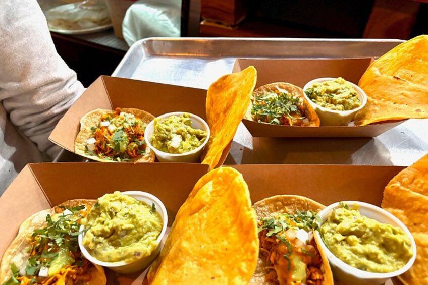 A tray with food items including tacos, guacamole, and tortillas. 1