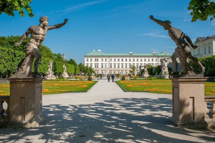 Un camino flanqueado por estatuas que lleva a un edificio grande con un jardín al frente. 2