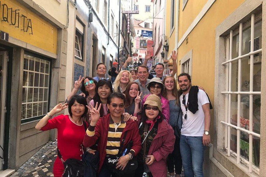 A group of people posing in a narrow street with buildings on either side. 2