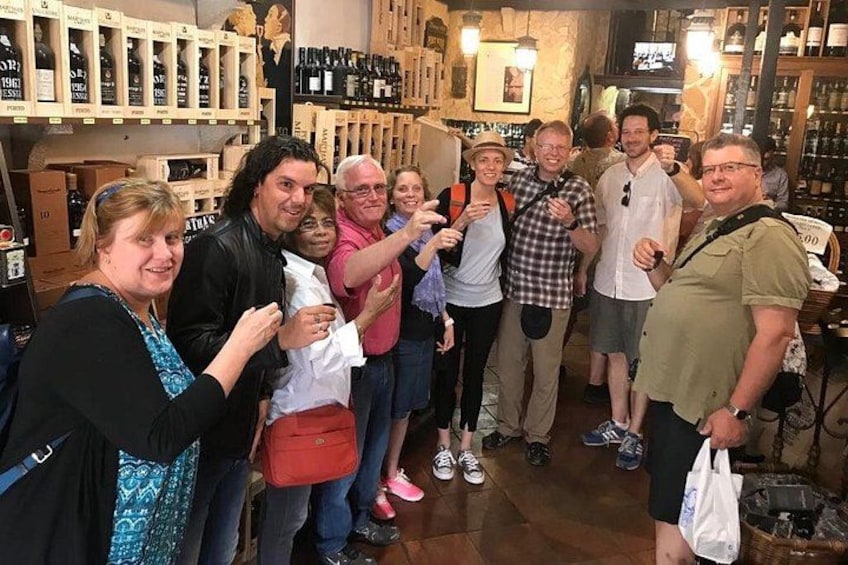 A group of people in a wine shop with shelves of wine bottles. 2