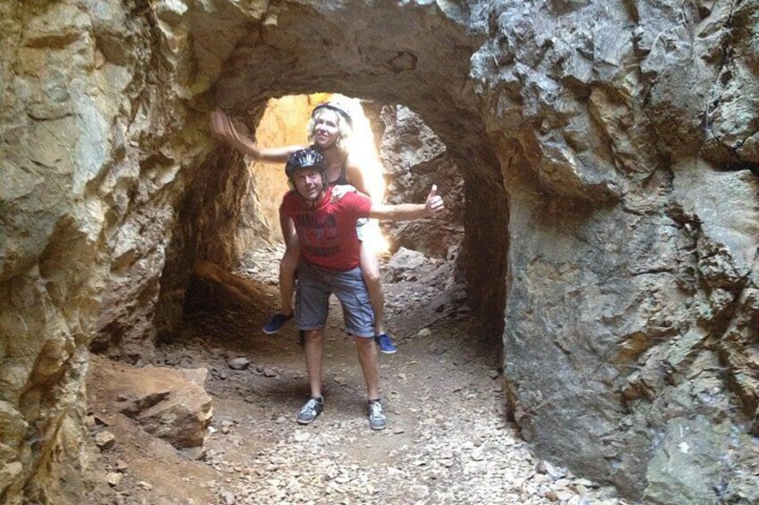 A person standing in a rocky cave with another person on their shoulders. 5