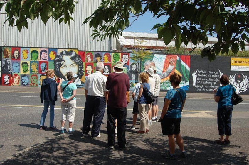 A mural on a wall with people standing in front of it. 1