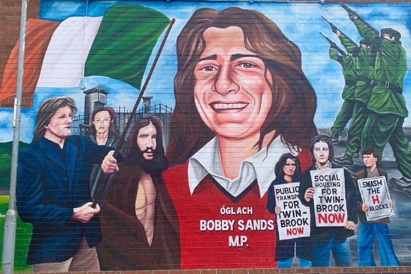A mural with a person in a red vest, a flag, and people holding signs. 2