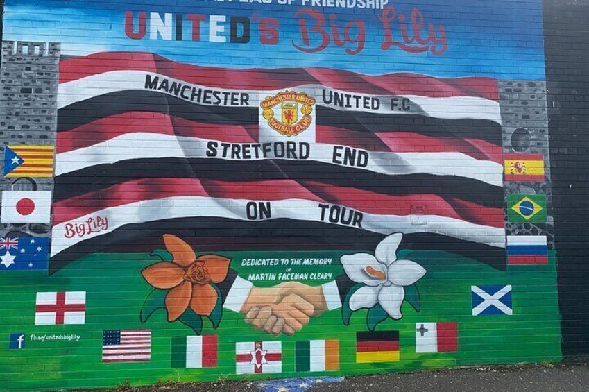 A mural with flags, Manchester United and Big Lily logos, and a dedication to Martin Man Cleary. 4