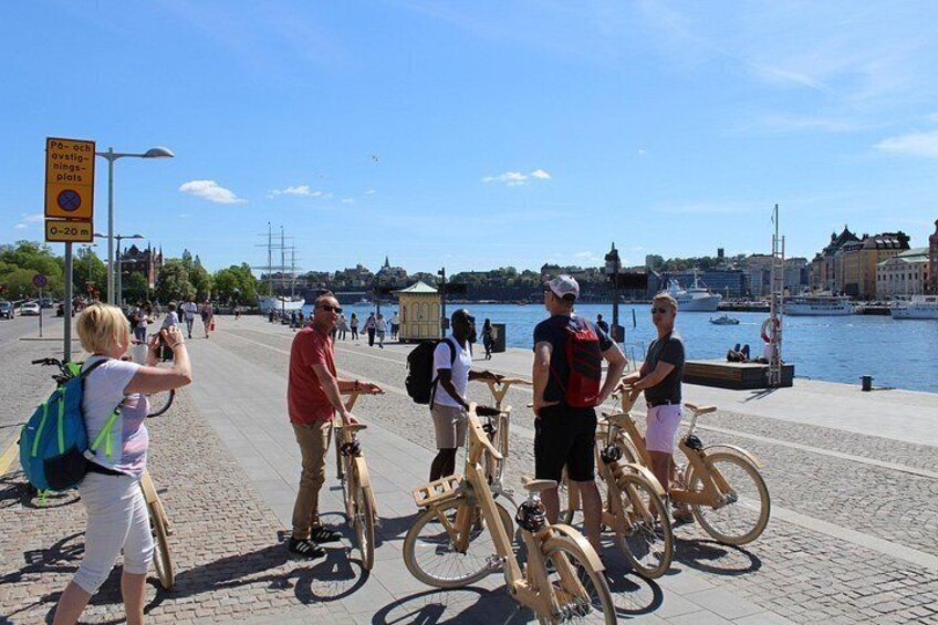 En gruppe mennesker på cykler ved en kaj, med et skilt der angiver 20 meters afstand til vandet. 2