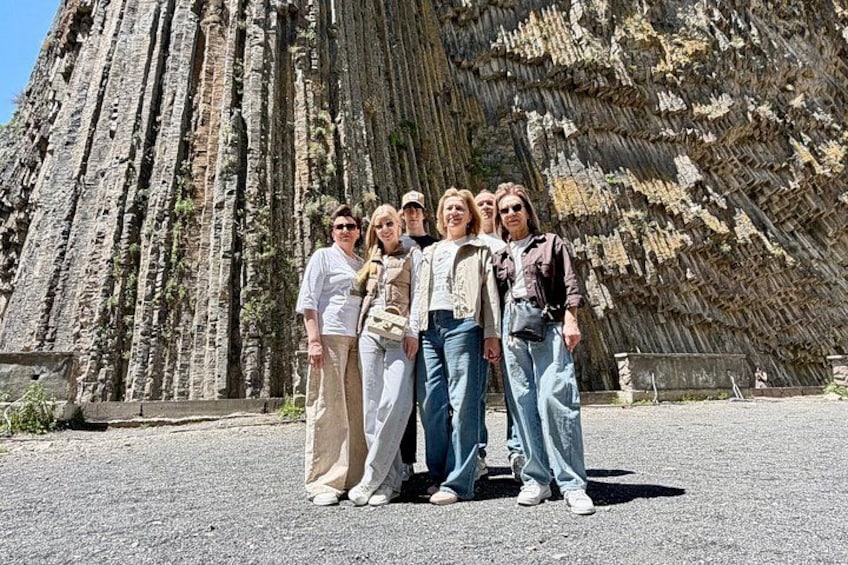 A group of people standing in front of a large, textured rock formation. 4