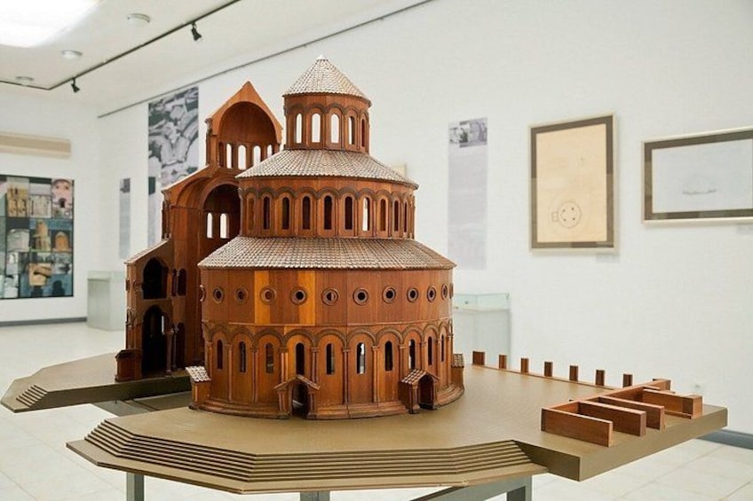 Un modelo arquitectónico detallado de una iglesia con ventanas arqueadas y una cúpula, expuesto en una mesa dentro de un museo. 3