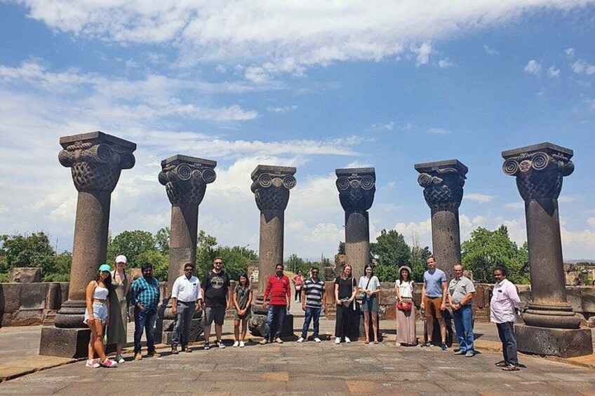 Un groupe de personnes se tient devant d’anciennes colonnes de pierre. 3