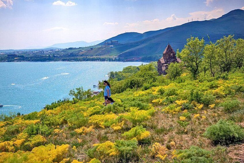 A person hiking on a grassy hill with a lake and mountains in the background. 2