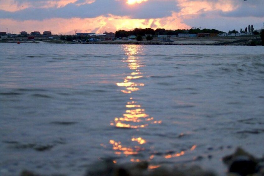Een zonsondergang boven het water, met zonneschitteringen op het oppervlak. 2