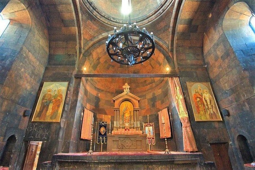 Ein Kircheninneres mit einem zentralen Altar, einer Chandelier und religiösen Gemälden an den Wänden. 4