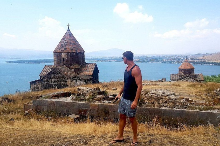 A man standing in front of a church with a lake in the background. 2