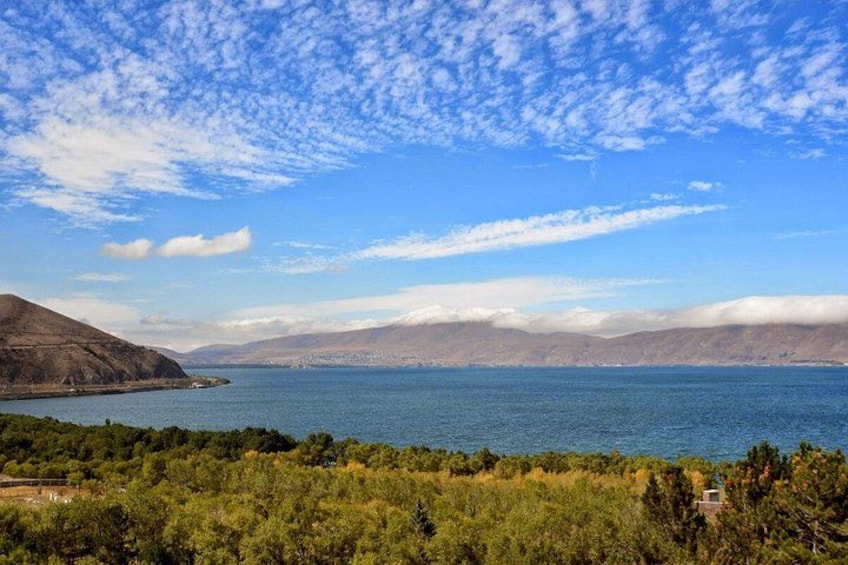 A coastal landscape with a clear sky, a body of water, and distant mountains. 4