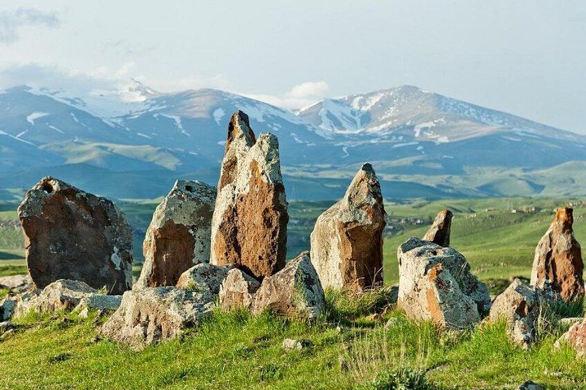 En stencirkel med et bjergrigt landskab i baggrunden. 4