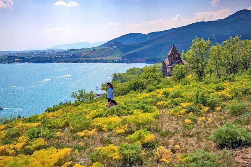 Una persona caminando por una colina cubierta de hierba, con un lago y montañas al fondo. 1