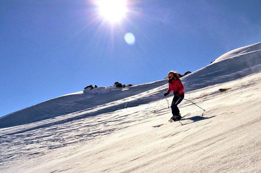 Una persona scia sulle piste innevate, con il sole che splende sullo sfondo. 4