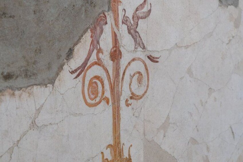A fresco with a central figure and two smaller figures on either side, set against a cracked wall. 3