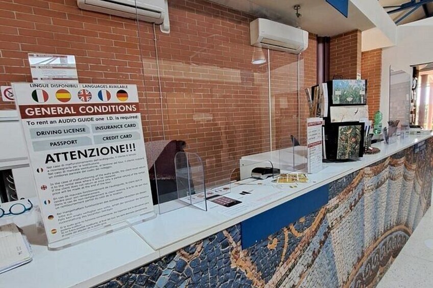 Una mesa de recepción con un cartel que enumera las condiciones de alquiler y los idiomas disponibles. 4