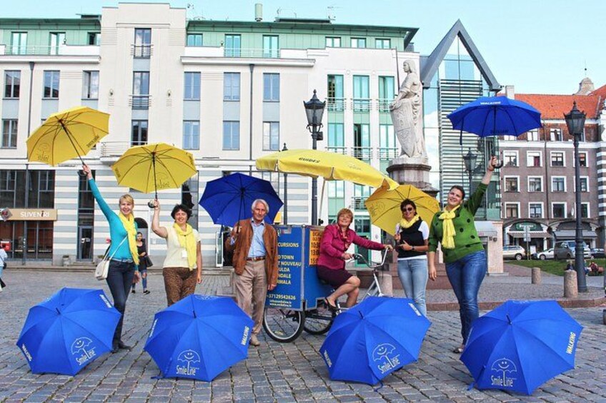 Des personnes se tiennent sous des parapluies devant un bâtiment orné d’une statue. 2