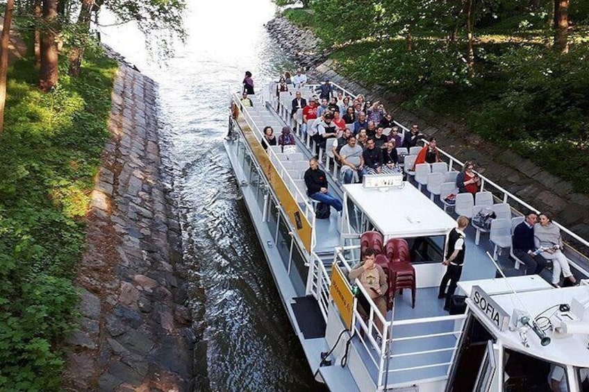 A riverboat with passengers, surrounded by greenery and stone walls. 4