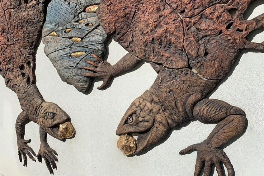 Una escultura grande y texturizada de un dinosaurio, con escamas y garras detalladas. 1