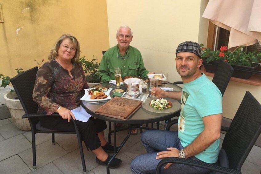 Tres personas sentadas en una mesa al aire libre, con comida y bebidas. 4