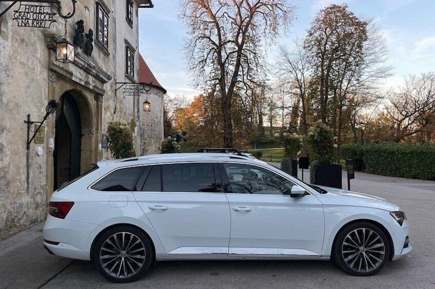 En hvid stationcar parkeret foran en bygning med et skilt, der viser 'HOTEL GRAND OUEST'. 3