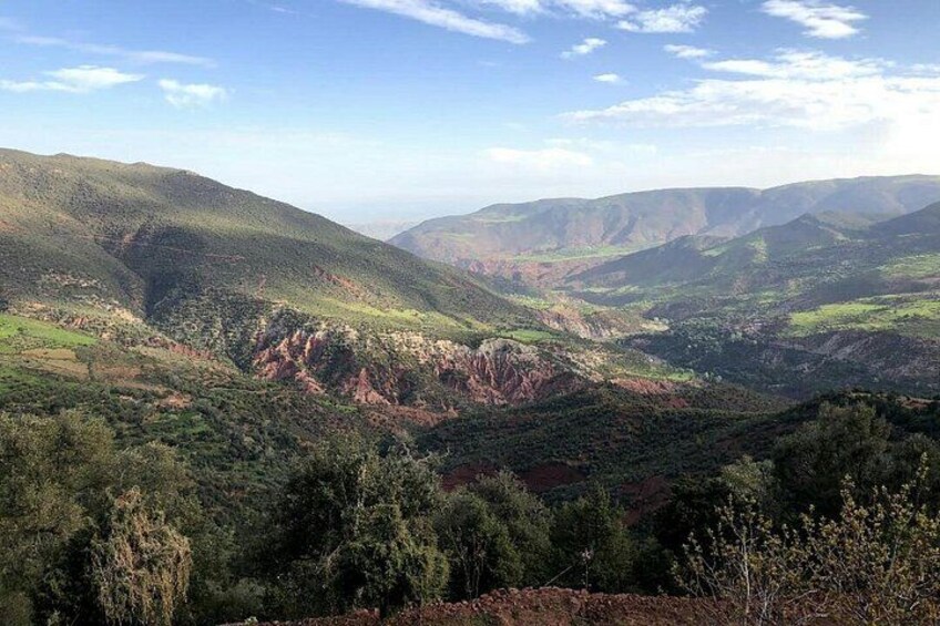 A mountainous landscape with green valleys and reddish-brown hills. 2