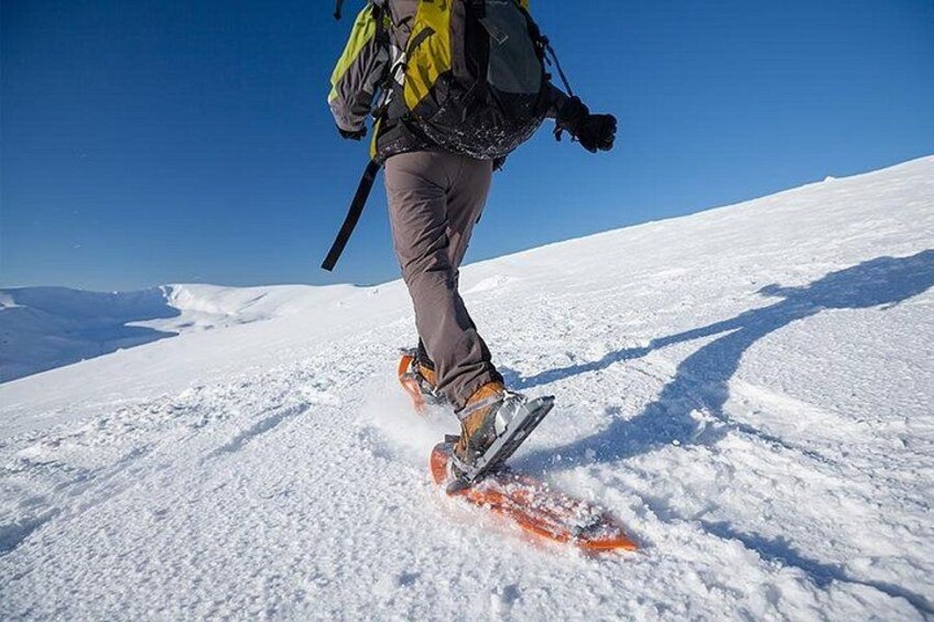 Une personne fait du ski sur une montagne enneigée, sous un ciel dégagé. 2