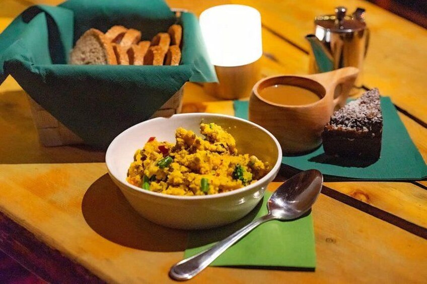 A bowl of food, a cup of coffee, and a piece of cake on a wooden table. 2