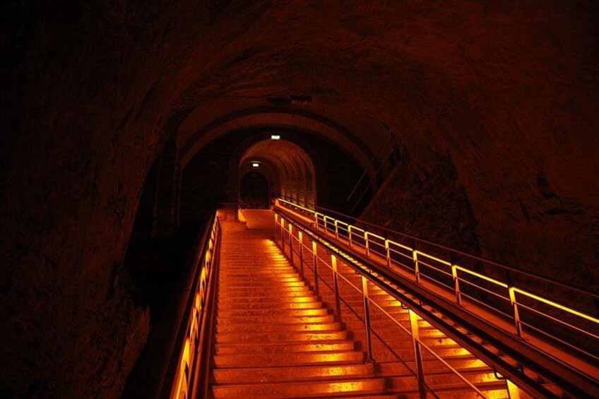 Un túnel de piedra con una escalera que lleva a una zona más luminosa. 4