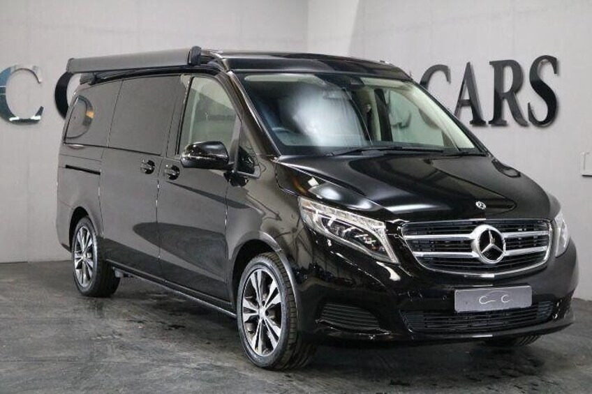 Un fourgon Mercedes-Benz Sprinter noir est garé à l’intérieur, avec un panneau indiquant « CARS » en arrière-plan. 2