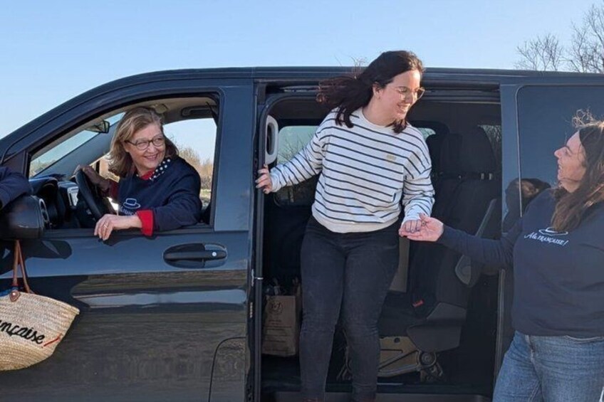 A vehicle with its door open, a person standing inside, and another person outside. 5