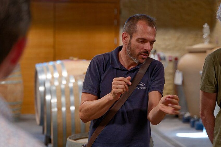 A man in a blue polo shirt with a logo, gesturing while speaking. 4