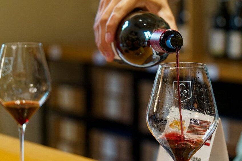 A hand pouring red wine into a glass. 2