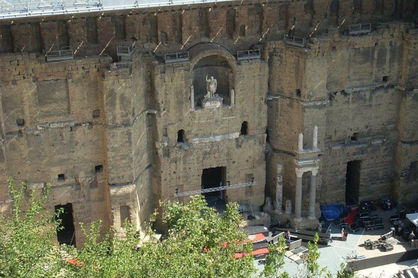Un edificio histórico de piedra con ventanas en arco y una estatua central. 2