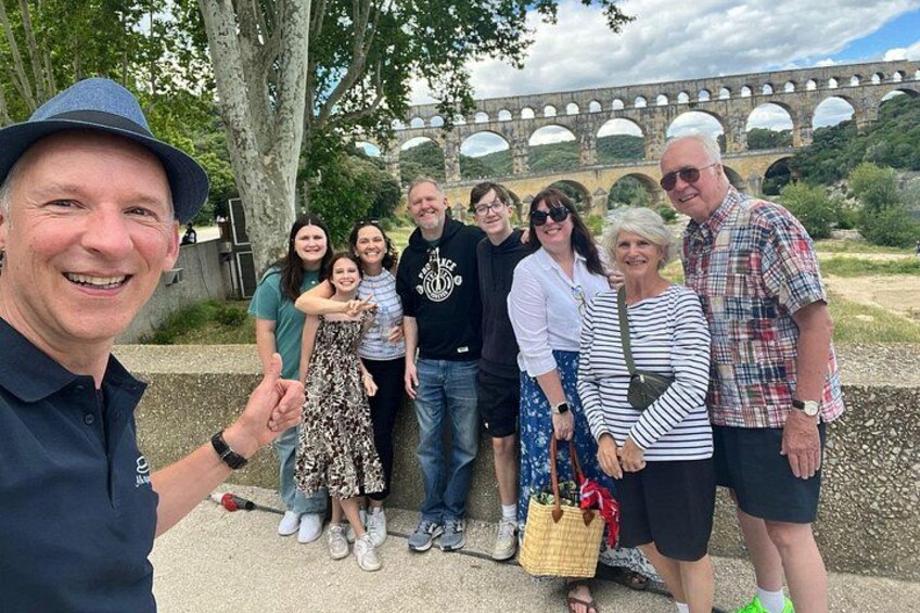 A group of people standing in front of a stone bridge with arches. 2