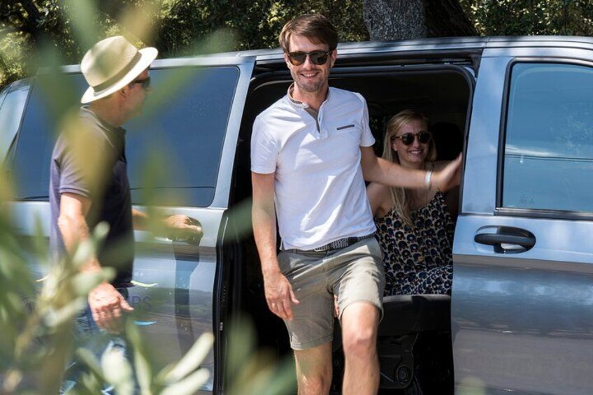 Una persona con camisa blanca y pantalones cortos caqui sale de una furgoneta plateada. 3