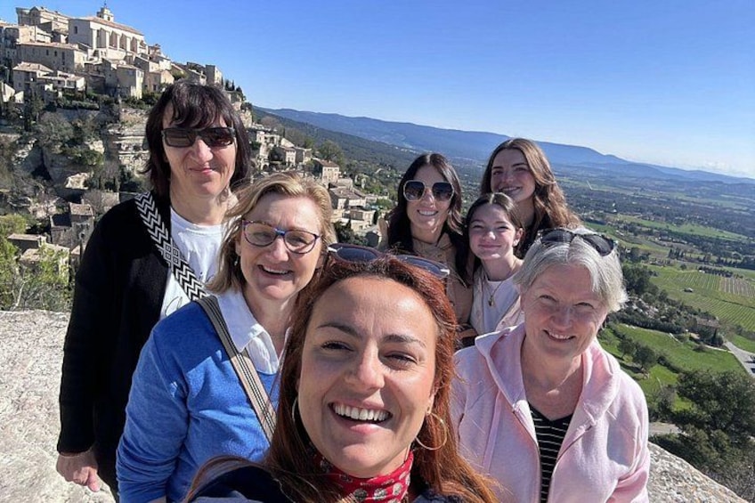 A group of people on a hill overlooking a historic town with buildings and a view of the countryside. 1